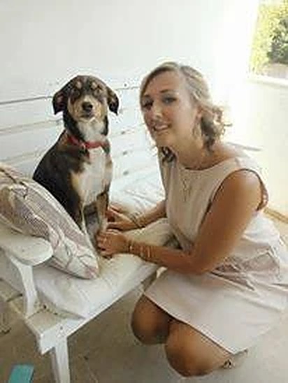 Julie smiling, sitting beside a friendly dog